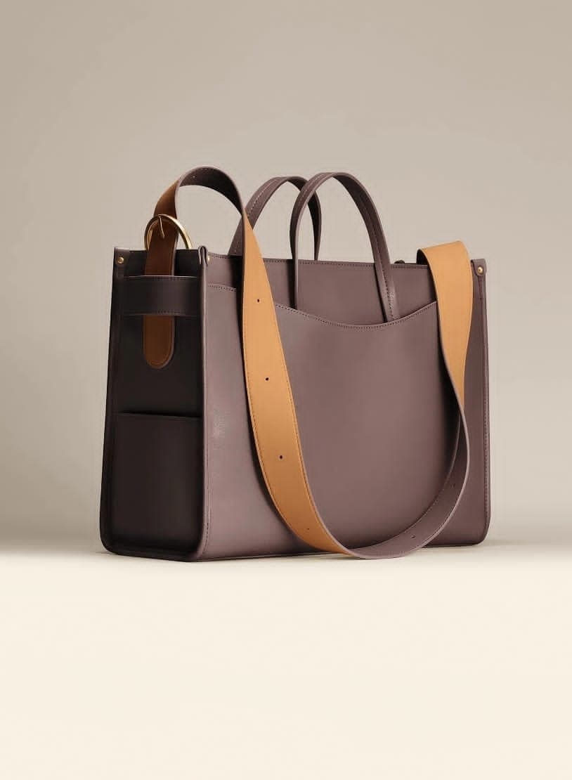 A structured two-tone leather tote bag in mauve-taupe with a wide tan adjustable shoulder strap and gold hardware